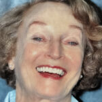 Full-face portrait of an older woman laughing joyfully and showing a complete set of secure, bright white dental implants from Smile Center Silicon Valley in Sunnyvale.